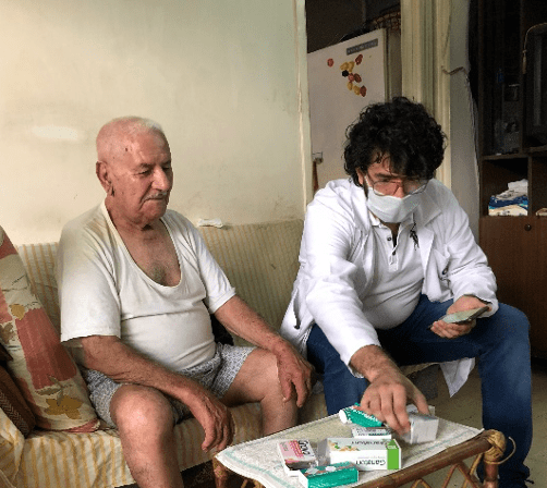 Darwiche Sibliny, an older Lebanese man, sits with his son as they look through health supplies