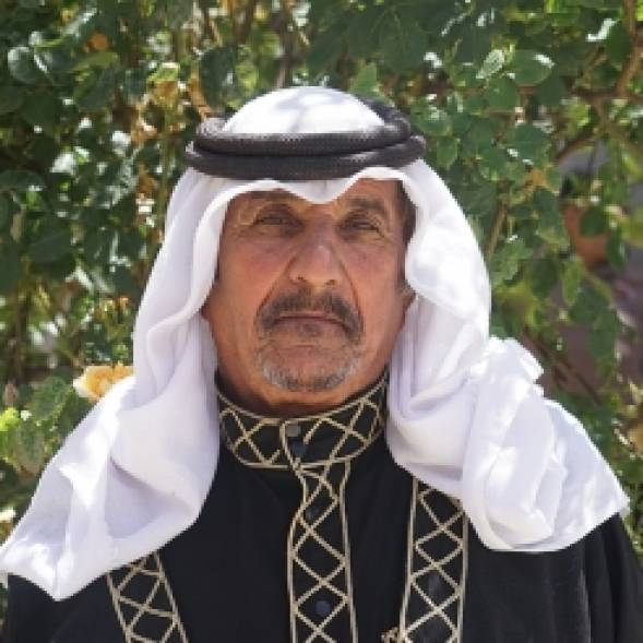 A Jordanian man in a keffiyeh looks towards the camera